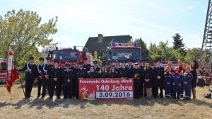Gruppe von Mitgliedern der Feuerwehr vor zwei Fahrzeugen