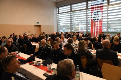 Viele Mitglieder der Feuerwehr an Tischen in einem Saal