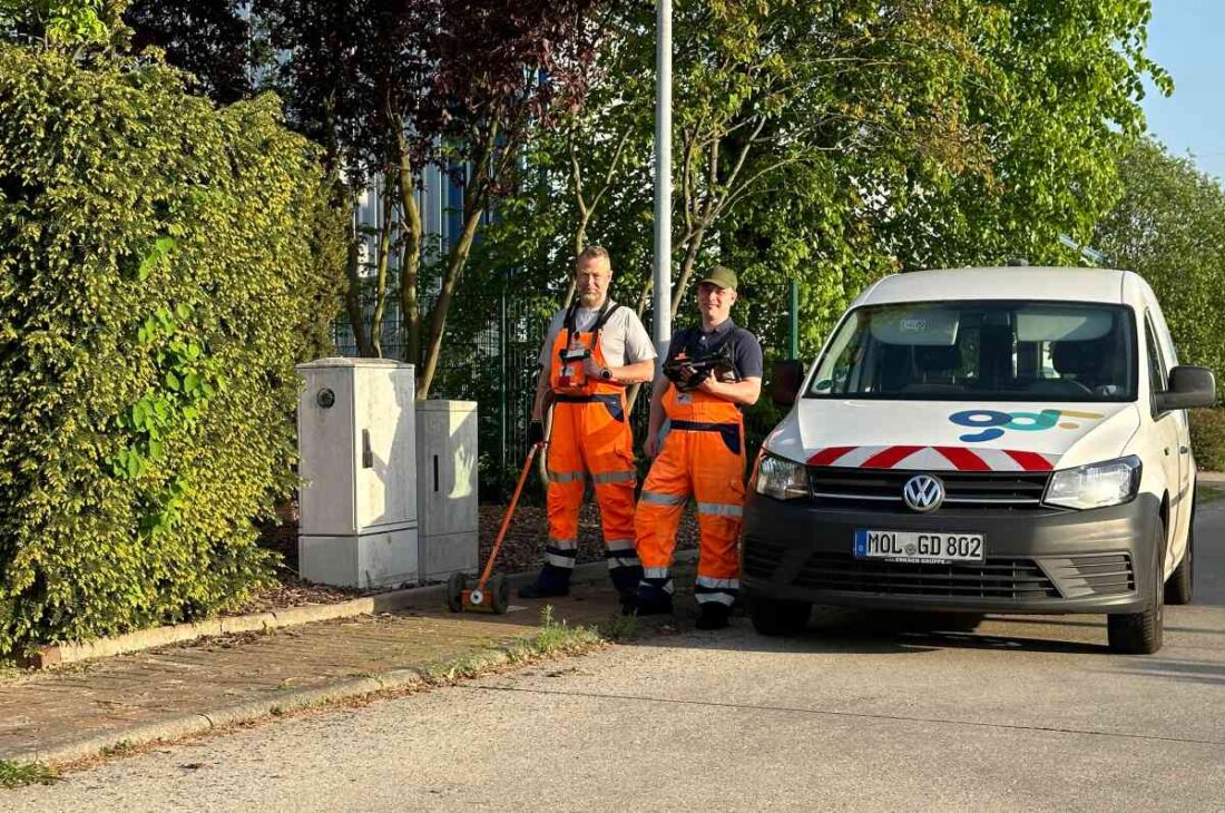 Zwei Personen der EWE stehen mit Spürgerät neben ihrem PKW.