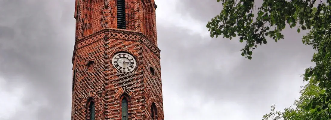 Ausschnitt des Kirchturms aus roten Ziegeln mit dem Ziffernblatt der Kirchturmuhr in Brodowin.