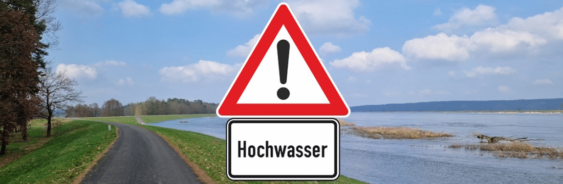 Hochwasserschutzdeich mit anstehendem Oder-Hochwasser im Hintergrund; Im Vordergrund ein Schild mit der Aufschrift "Achtung, Hochwasser"