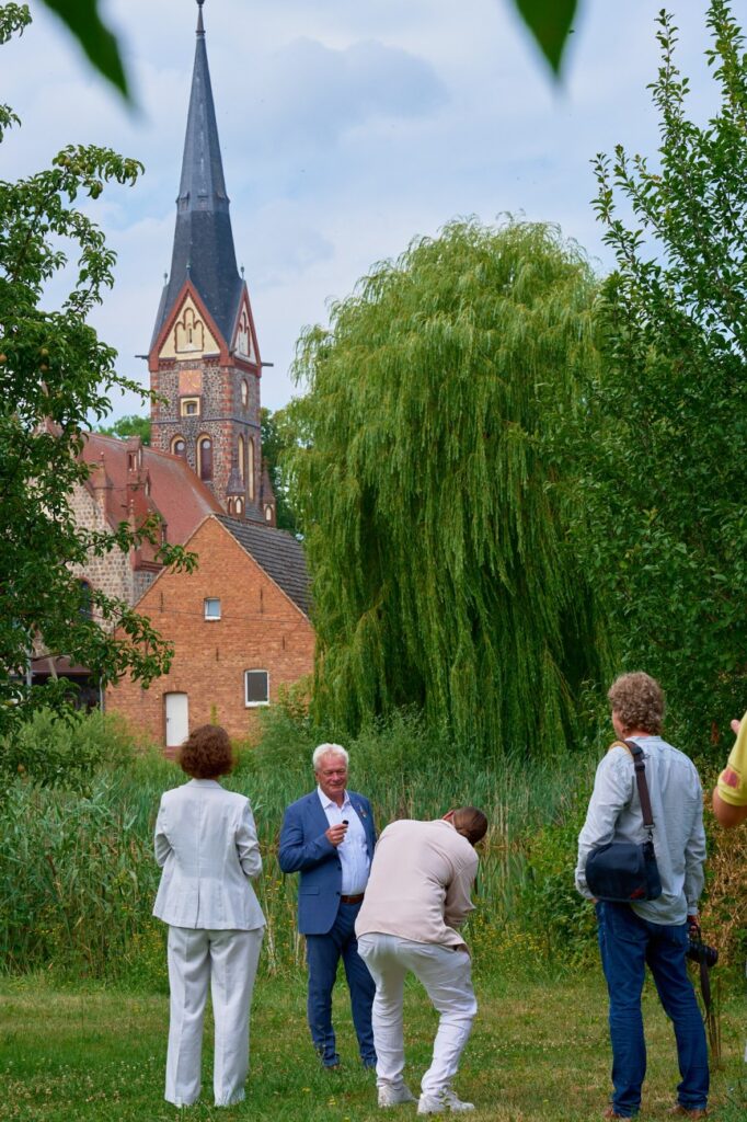 Mehrere Personen im Grünen, im Hintergrund eine Kirche