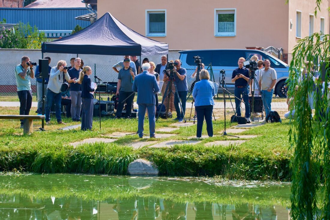 Gruppe von ca. 20 Personen, im Vordergrund ein Teich.