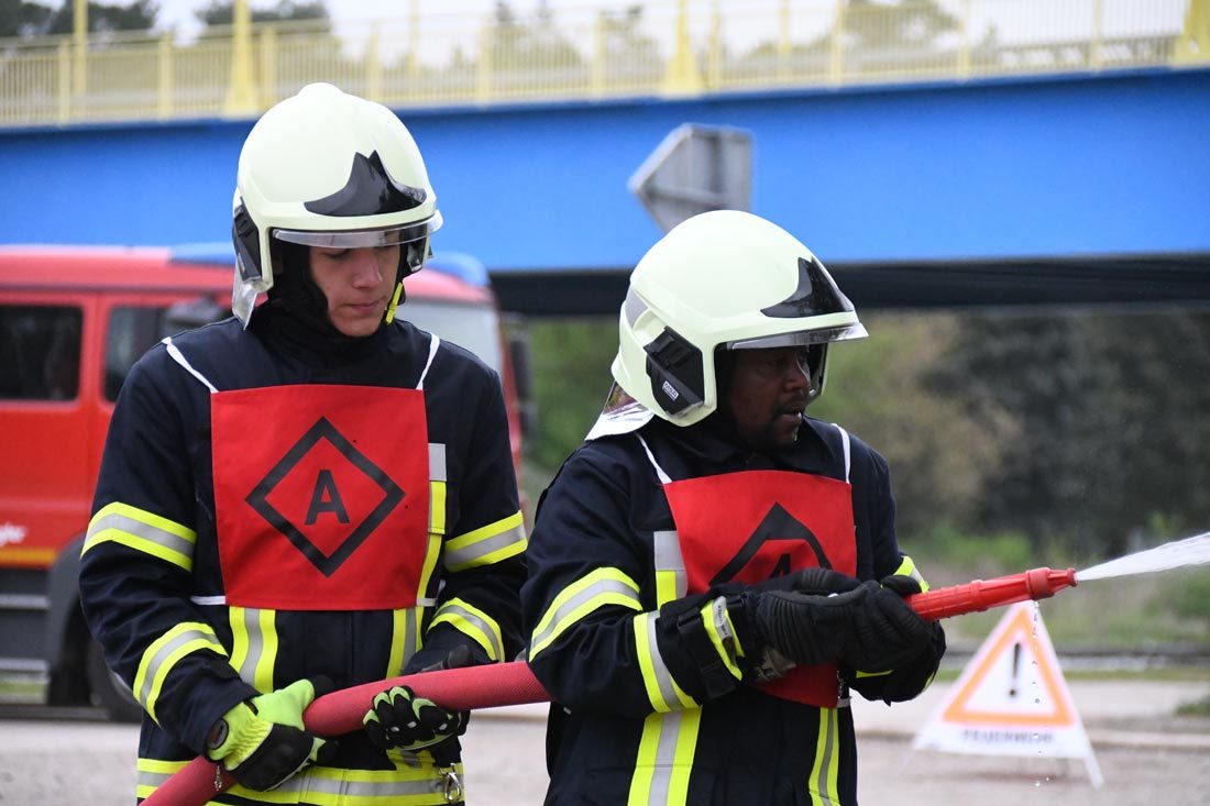 Zwei Mitglieder der Feuerwehr halten einen Löschschlauch