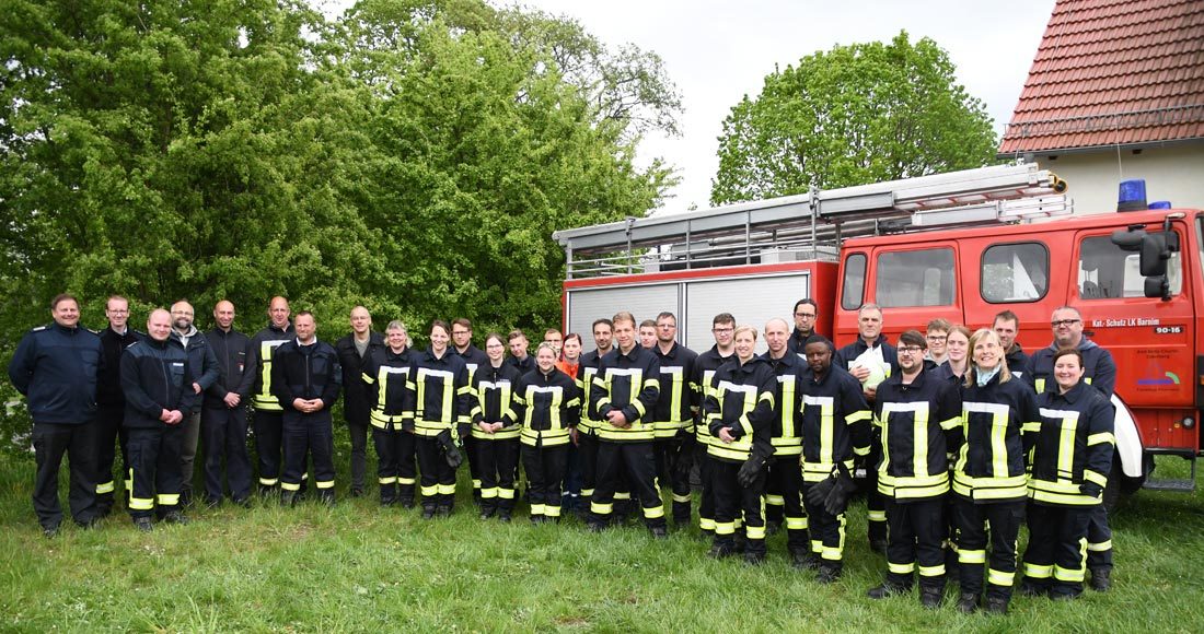 Viele Mitglieder der Feuerwehr vor einem Feuerwehrfahrzeug.