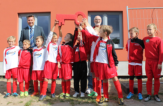 Fußballkinder vor einem roten Haus.