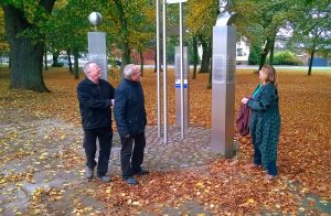 Drei Personen vor einer Metallbüste