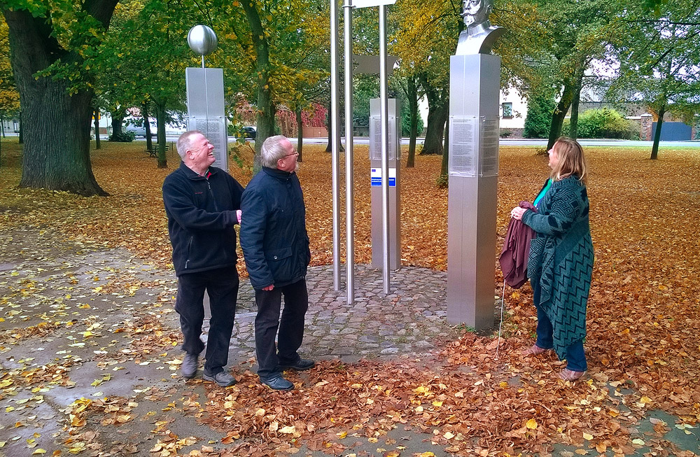 Drei Personen vor einer Metallbüste