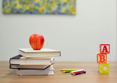 Tisch mit Büchern, Buntstiften und Würfeln mit den Buchstaben A, B und C.