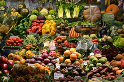 Gemüsestände und Obststände mit Kürbissen, Kohl, Trauben, Äpfeln, Tomaten, Ingwer und weiteren Sorten auf einem Markt.