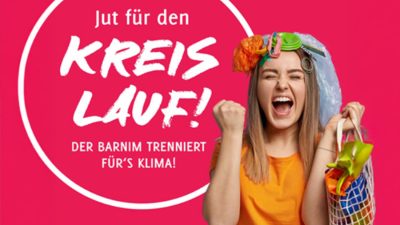 Jubelnde Frau mit Müll auf dem Kopf und einer Tasche mit Müll.