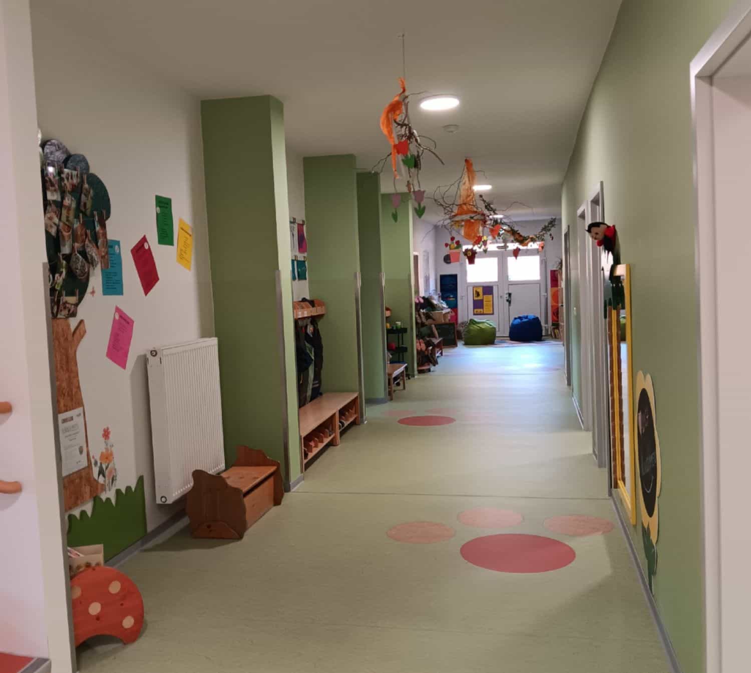 Langgezogener Flur mit Garderoben und Bänken für Kinder an den Seiten.