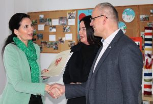 Ein Frau übergibt einem Mann einen Bescheid.