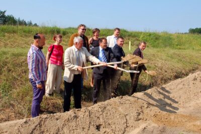 Mehrere Personen heben mit einem Spaten Sand aus.