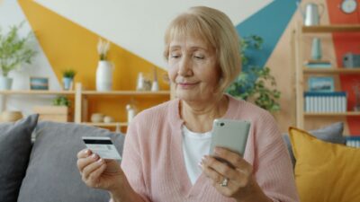 Ältere Frau mit Kredikarte und Smartphone